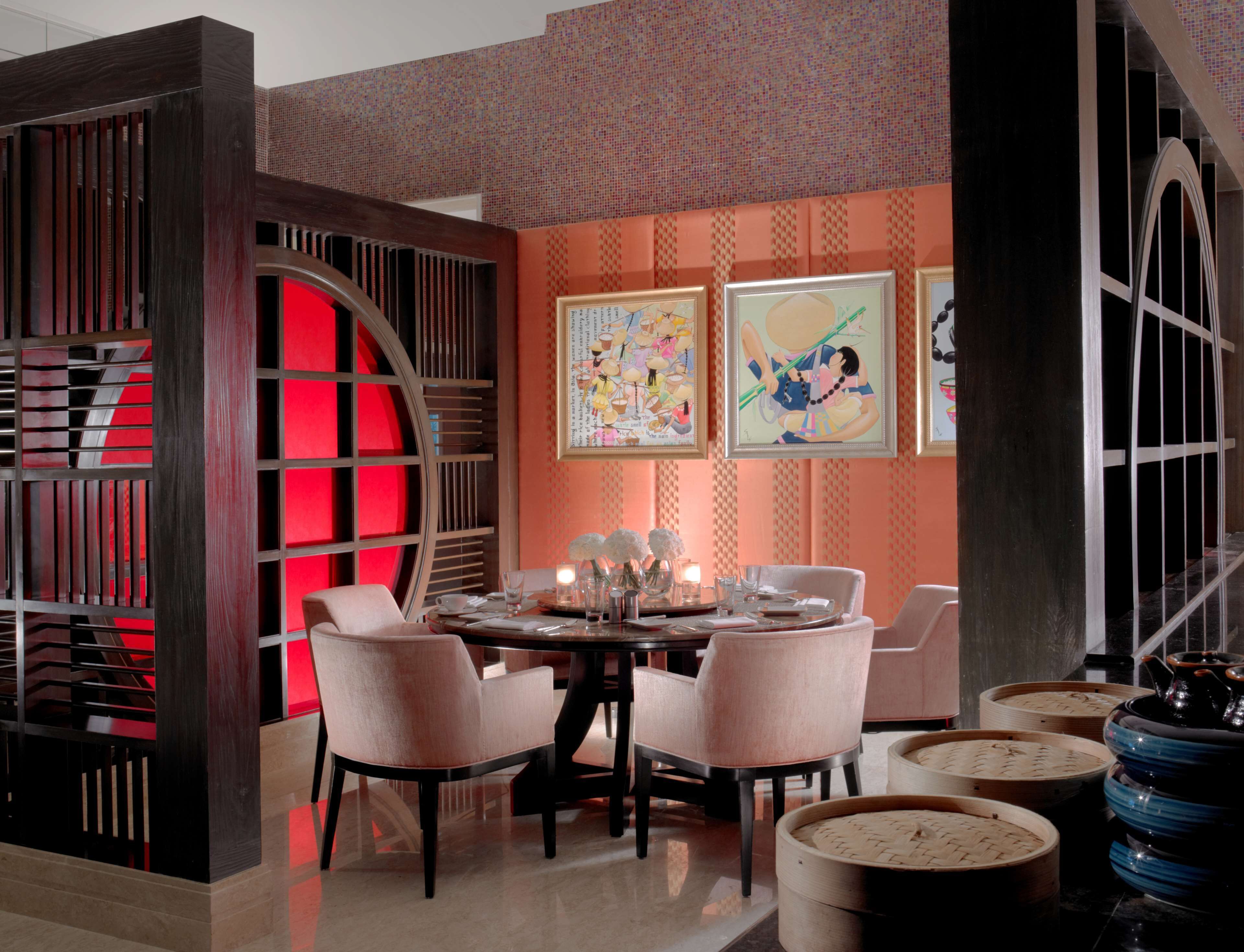 A dining area with a round table, four chairs, and a decorative wall with framed artwork.