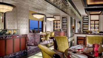 A restaurant with a marble bar, gold chairs, and a view of the water.