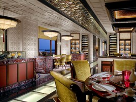 A restaurant with a marble bar, gold chairs, and a view of the water.