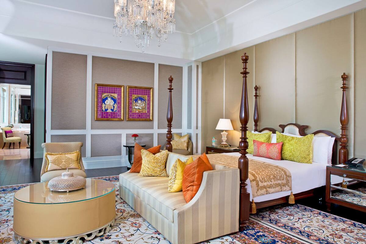 Ein geräumiges Hotelzimmer mit einem großen Bett, einer Couch, einem Glastisch und einem Kronleuchter.