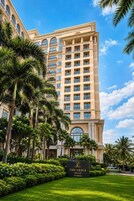 Un hotel de varios pisos con estilo arquitectónico clásico, que destaca por su entrada imponente y abundante vegetación.