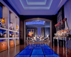 Un hall de hotel con una zona de estar central, un mostrador de recepción y un amplio ventanal con vistas.