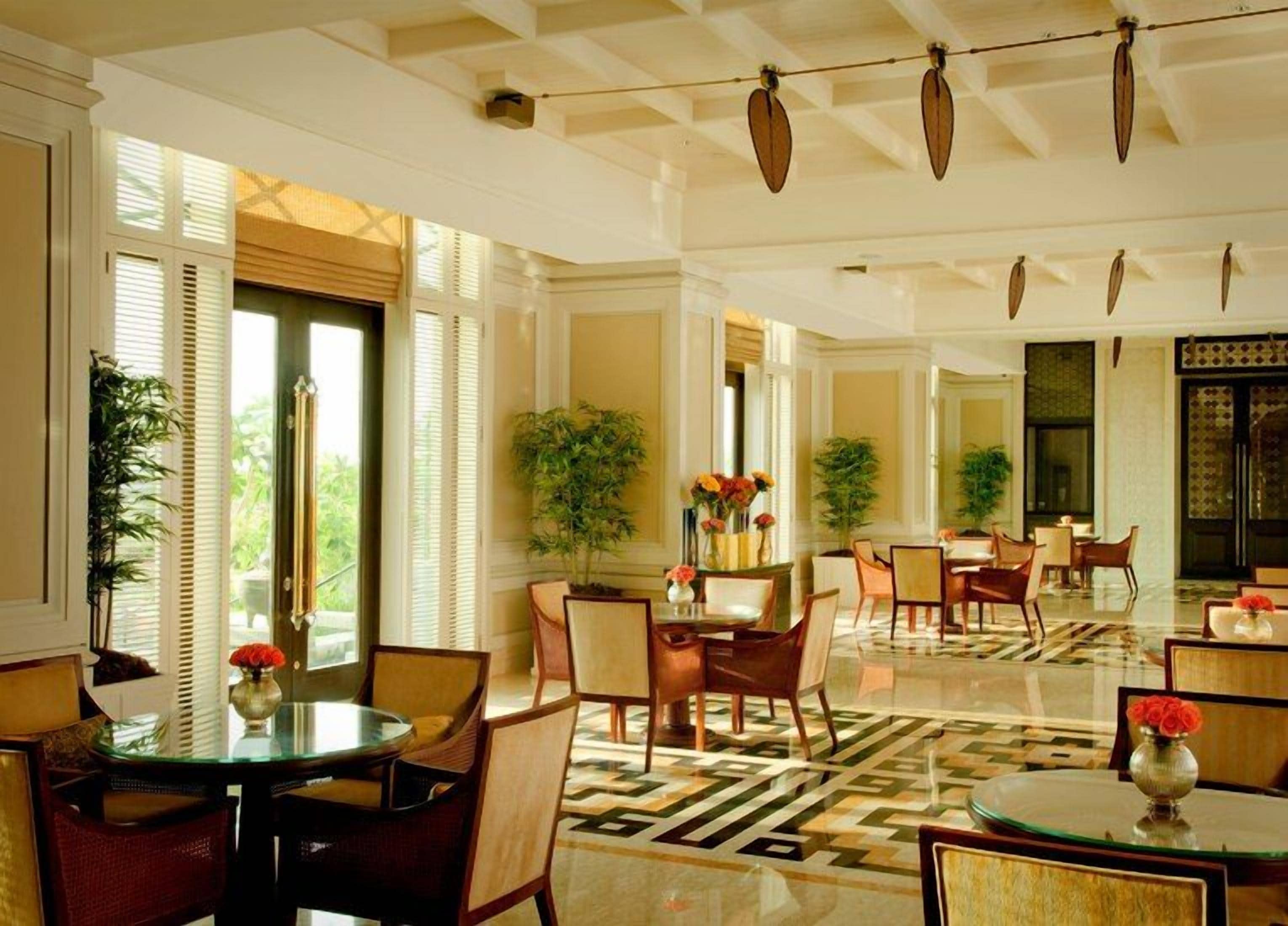 A spacious hotel lobby with multiple seating areas, large windows, and a patterned floor.