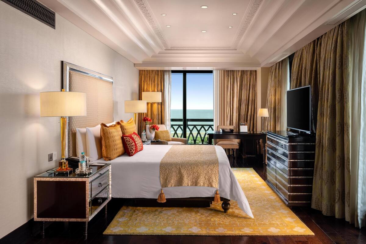 Ein geräumiges Hotelzimmer mit einem großen Bett, zwei Nachttischen, einem Schreibtisch und einem Fernseher. Das Zimmer verfügt über einen Balkon mit Meerblick.
