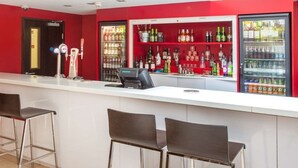Eine Bar mit einer weißen Theke, roten Wänden und mehreren Regalen voller Flaschengetränke.
