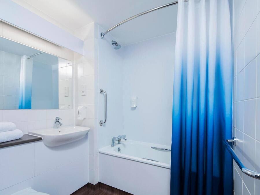 A modern bathroom with a white sink, mirror, and toilet.