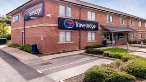 Un hôtel Travelodge avec une façade en briques, de nombreuses fenêtres et une entrée abritée.