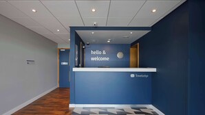 Un espace d’accueil avec un mur bleu, une horloge et une pancarte indiquant « Bonjour et bienvenue ».