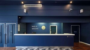 A reception desk with a "hello & welcome" sign, a clock, and a "Travelodge" logo. - Travelodge Brighton Seafront (Brighton)