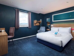 A hotel room with a bed, a desk, a chair, a window with curtains, a painting on the wall, and a view of the sky. - Tl Kingston Upon Thames Centrl (Kingston Upon Thames)