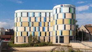 A Travelodge hotel with a unique striped facade, a reflection pool, and a bridge leading to the entrance. - Travelodge Maidstone Central (Maidstone)