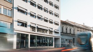Un edificio moderno con varios pisos, ventanas amplias y escaparate con señalización iluminada.