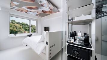 Una habitación de hotel moderna con cama, un separador de vidrio con la etiqueta 'módulo 504', una zona de café y vistas a zonas verdes.