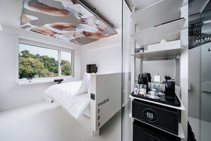 Una habitación de hotel moderna con cama, un separador de vidrio con la etiqueta 'módulo 504', una zona de café y vistas a zonas verdes.