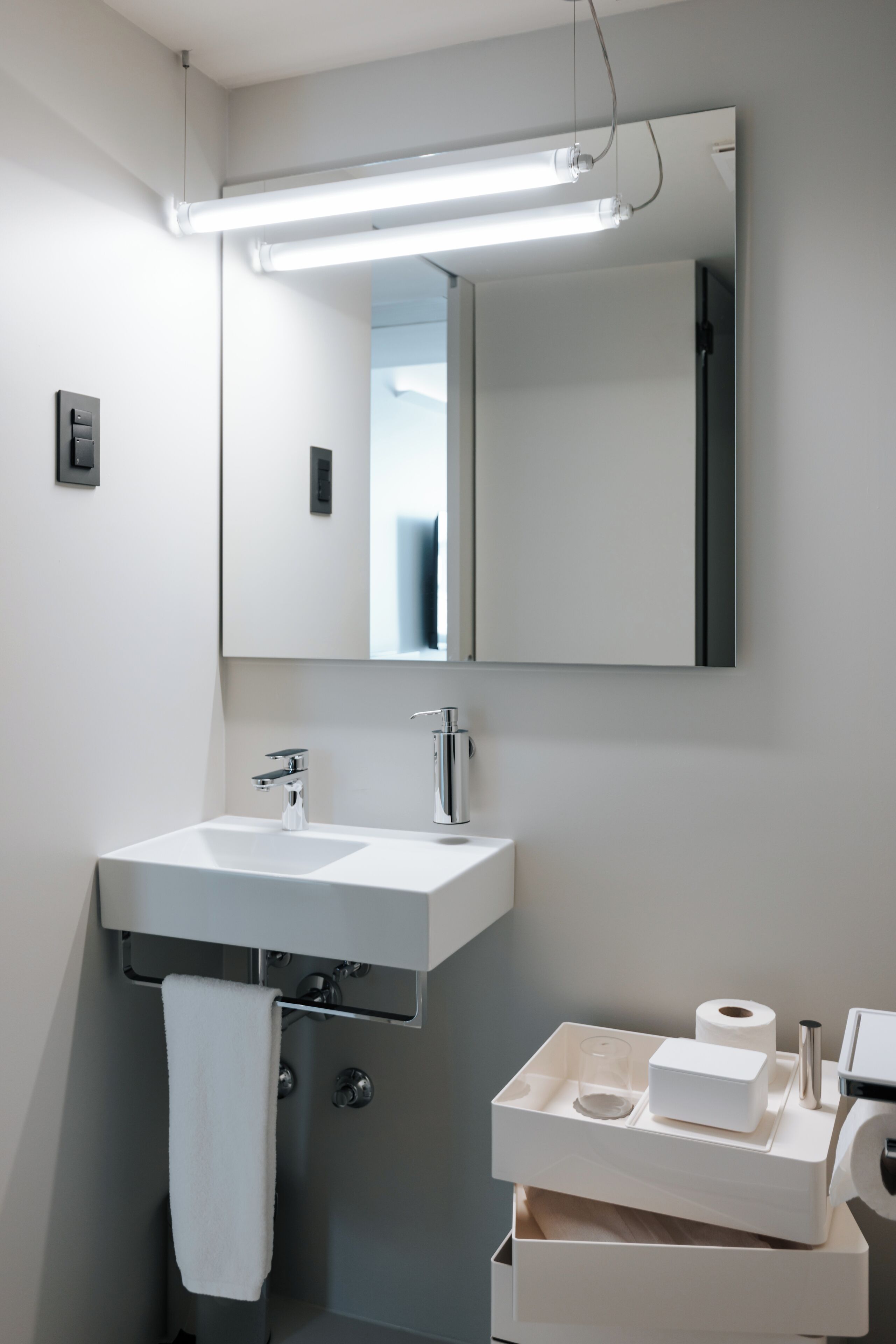 Une salle de bain moderne avec un lavabo blanc, un miroir et un porte-serviettes.