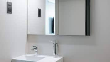 Une salle de bain moderne avec un lavabo blanc, un miroir et un porte-serviettes.