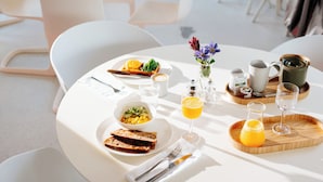 Una escena de desayuno con un plato de comida, un vaso de jugo de naranja y una taza de café sobre una mesa.