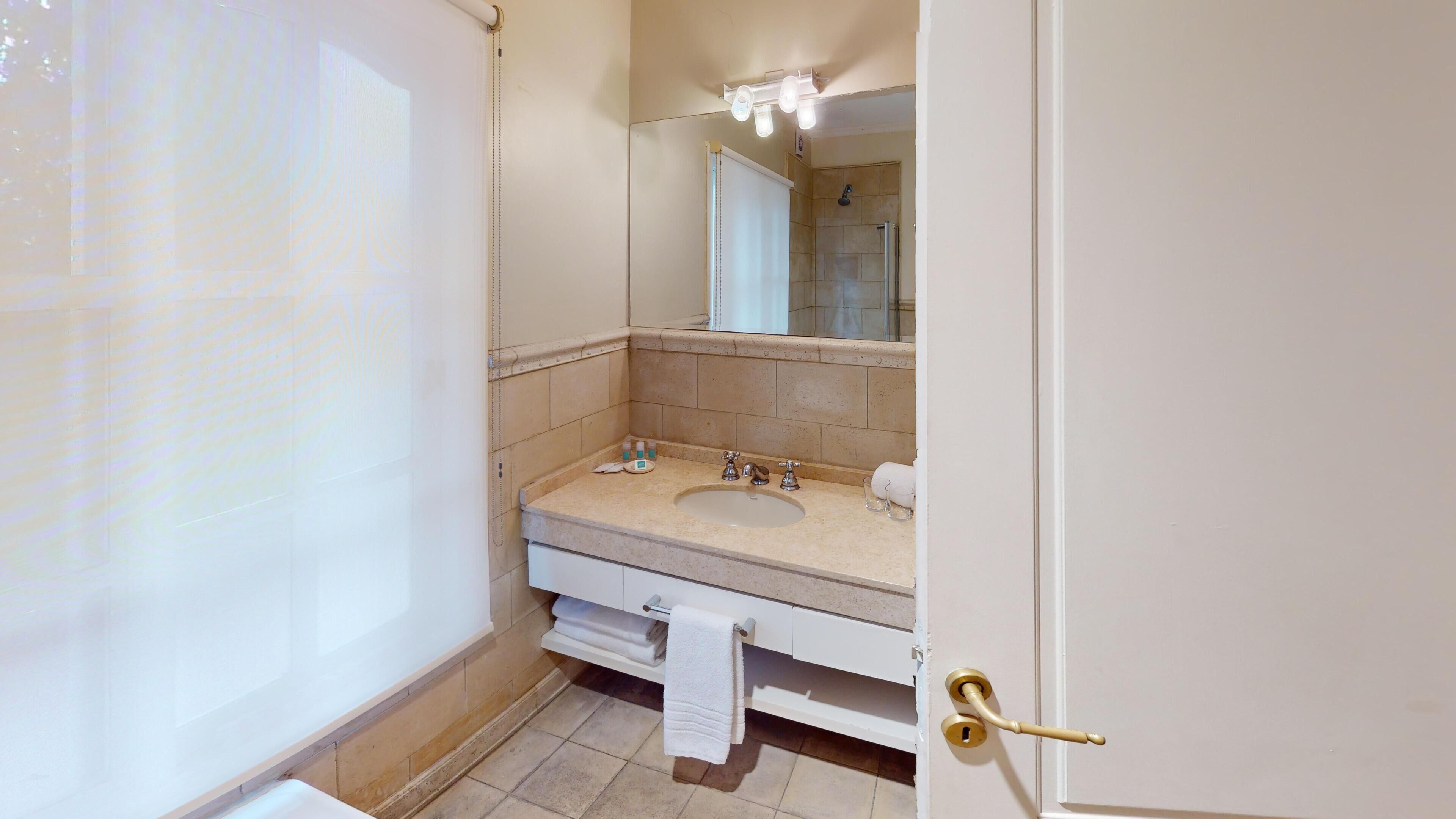 A bathroom with a sink, mirror, towel rack, and shower curtain.