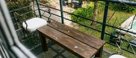 Una mesa de madera con un banco de metal en un balcón.