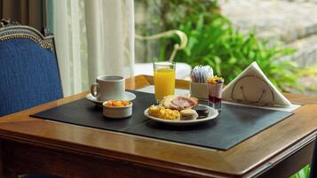 Una mesa de desayuno con una taza, jugo de naranja, huevos revueltos, jamón y un muffin.