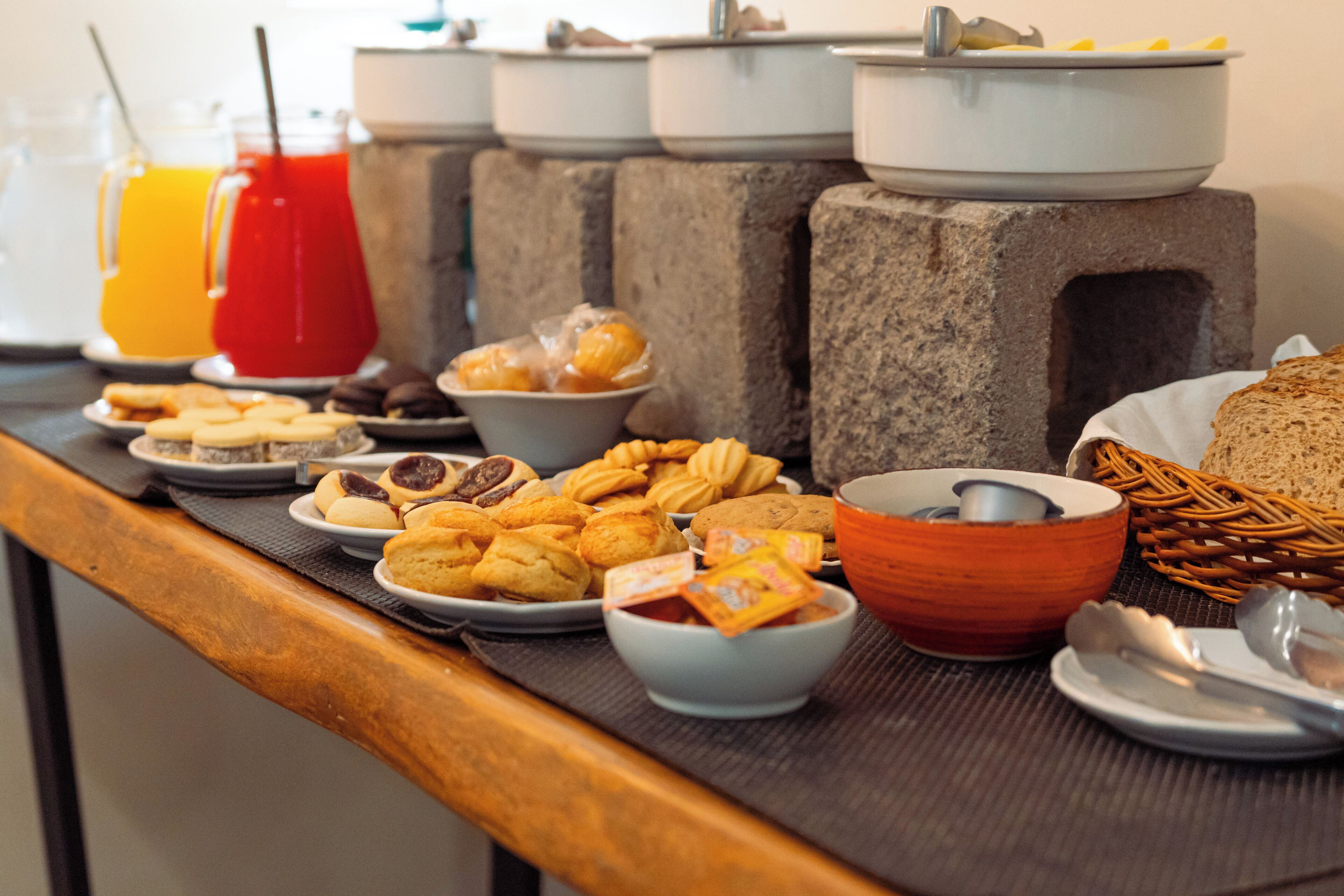 A breakfast buffet with various pastries, cookies, and a fruit drink.