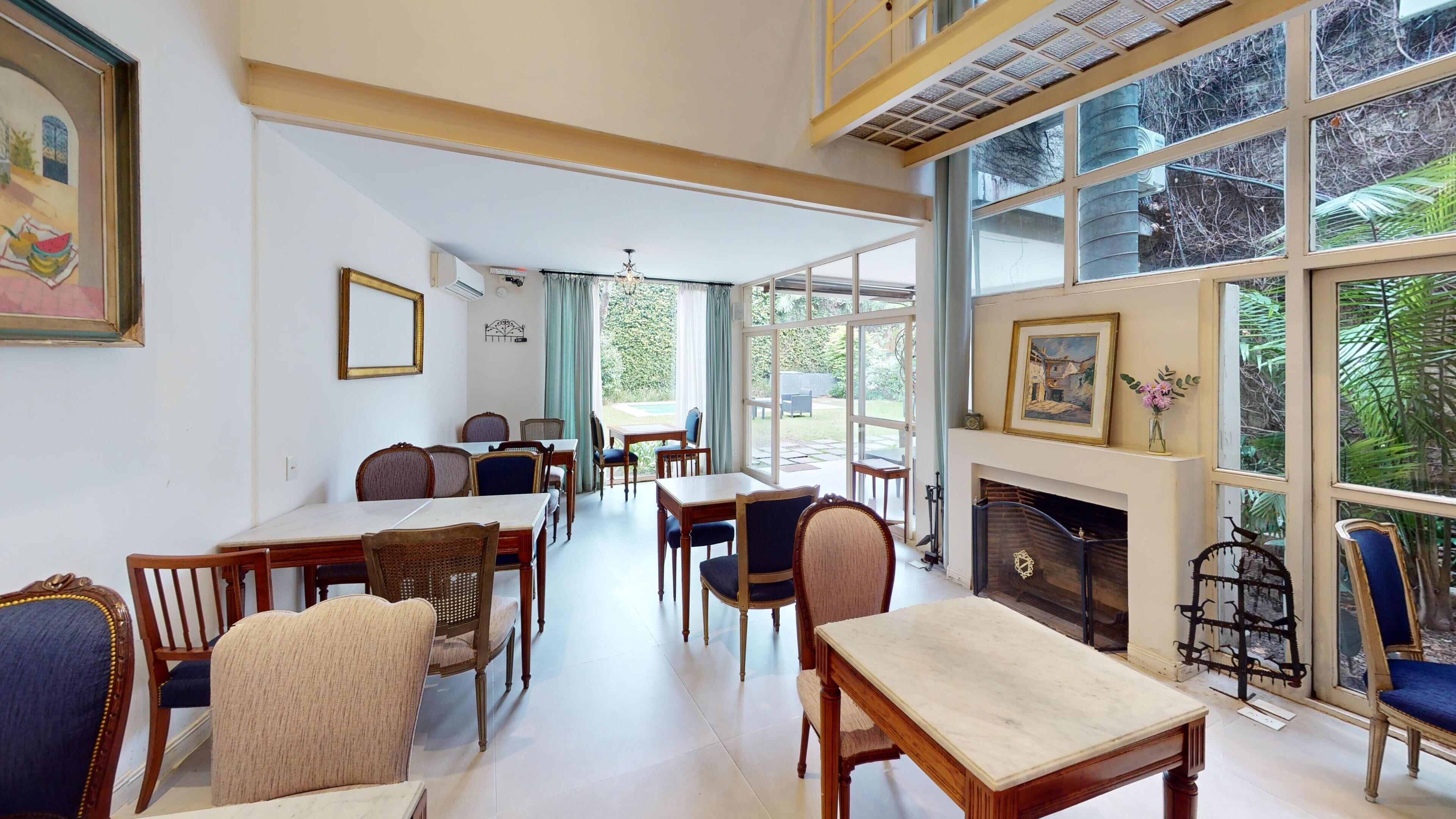 A spacious room with a fireplace, large windows, and a dining area with wooden furniture.