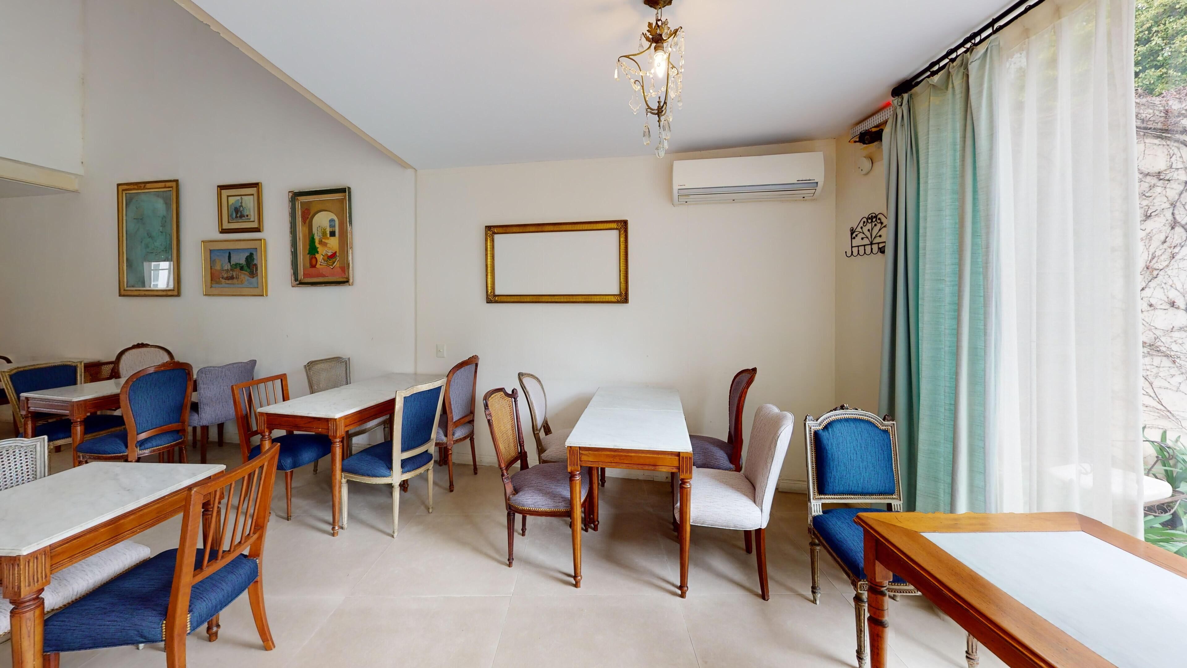 A dining area with wooden tables and chairs, a chandelier, and framed pictures on the wall.