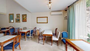 A dining area with wooden tables and chairs, a chandelier, and framed pictures on the wall.