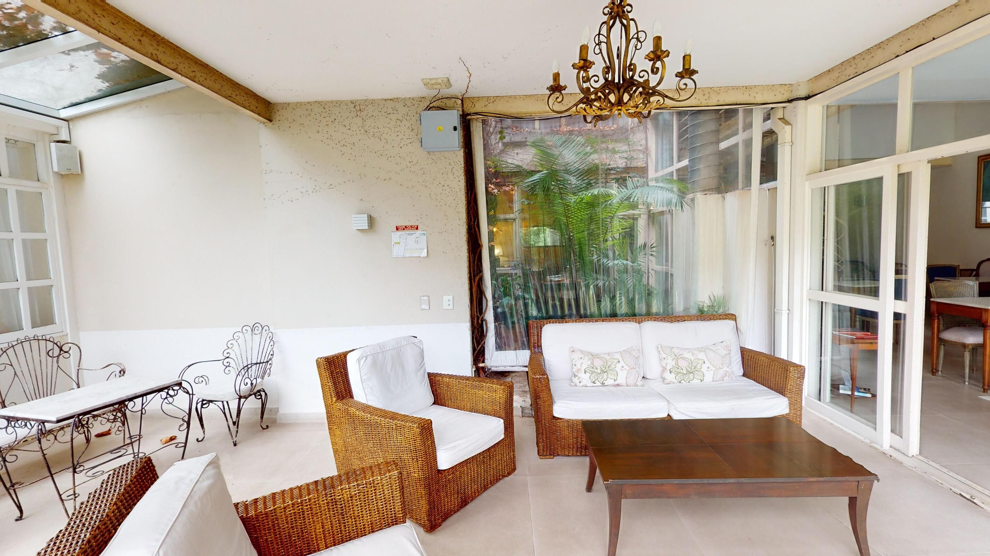 A room with wicker furniture, a wooden table, and a glass door leading outside.
