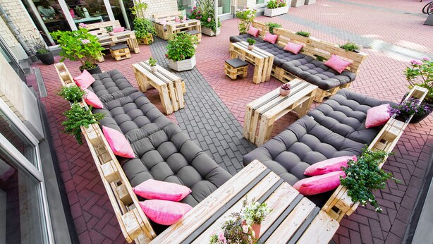 An outdoor seating area with wooden furniture and potted plants. - CALMA Berlin Mitte (Berlin)