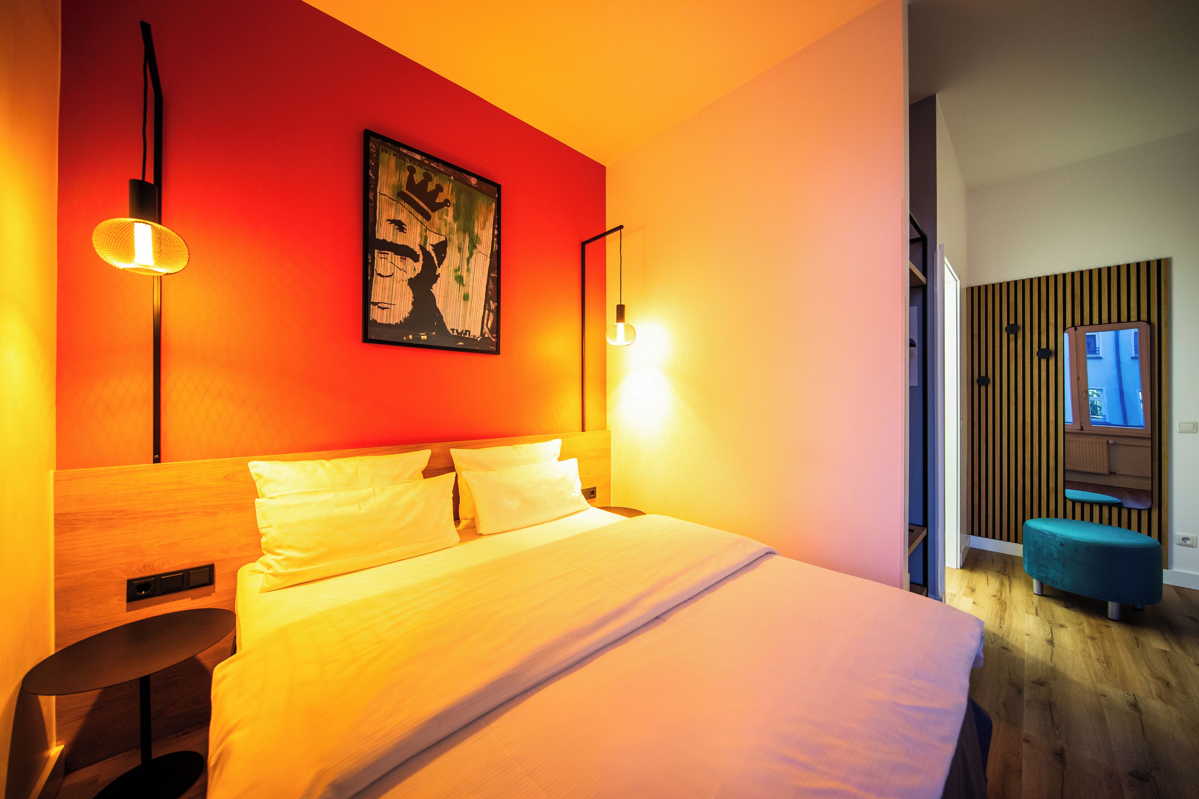 A modern hotel room with a large bed, two bedside lamps, a painting on the wall, and a wooden panel wall.