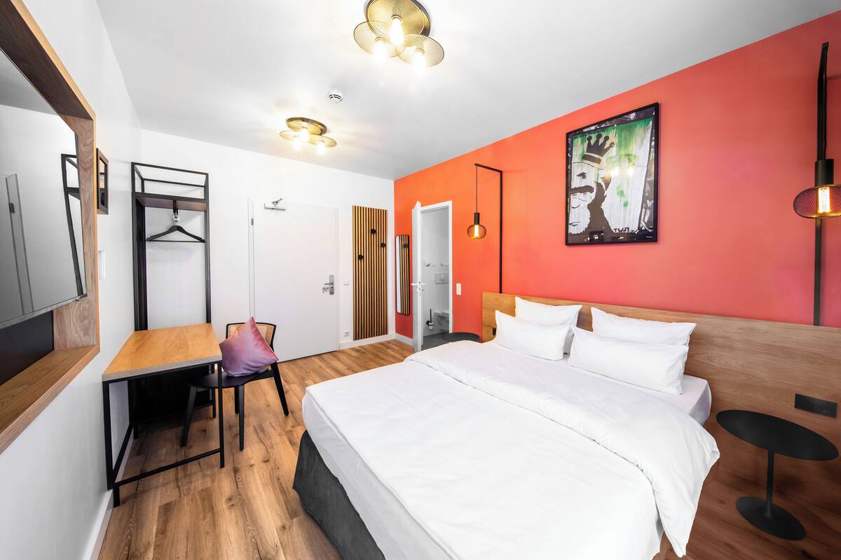 A modern hotel room with a wooden bed, a desk, and a chair.