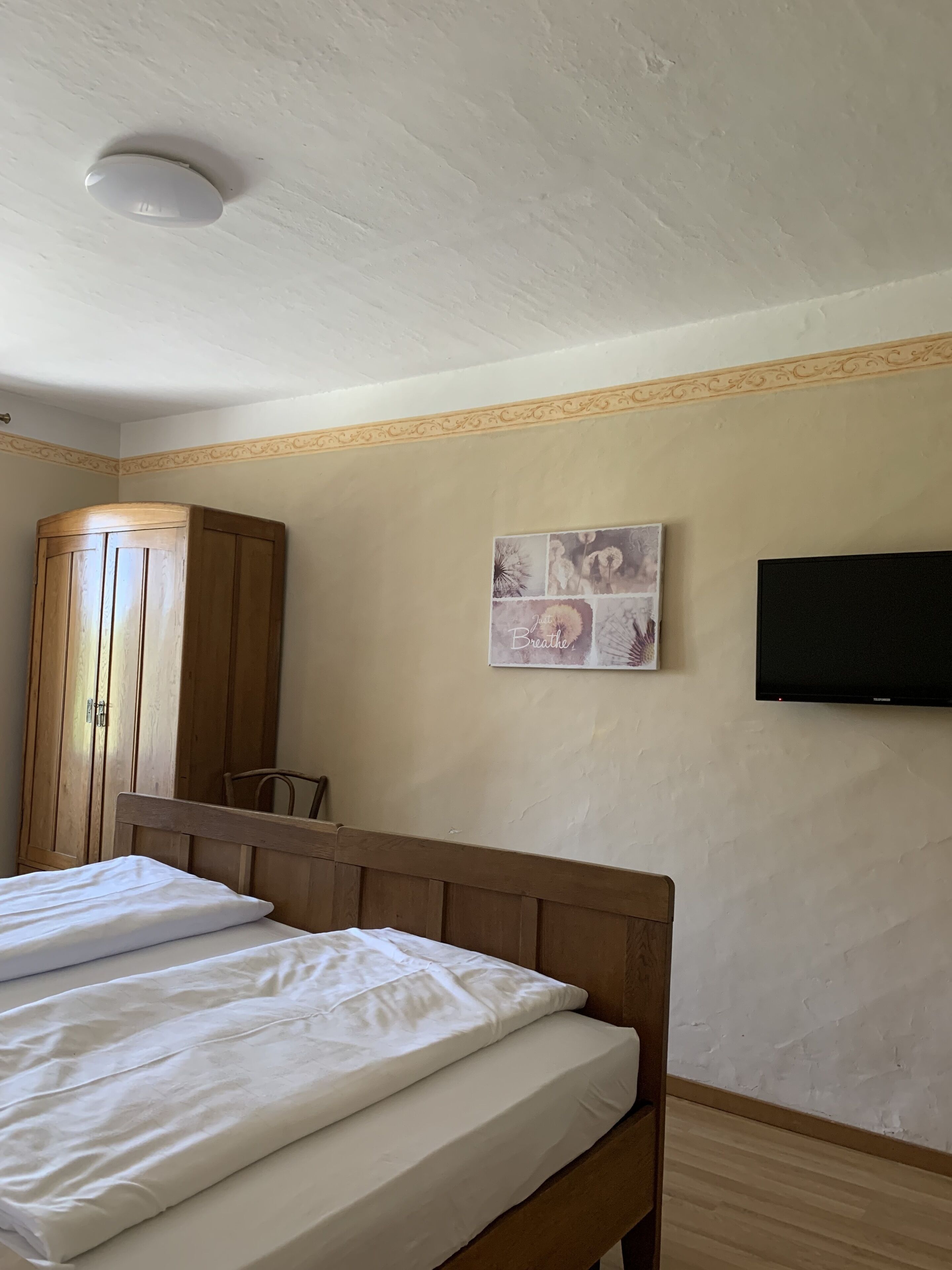 Ein Schlafzimmer mit einem hölzernen Bett, einem Kleiderschrank, einem Flachbildfernseher und einem an der Wand befestigten Kunstwerk.