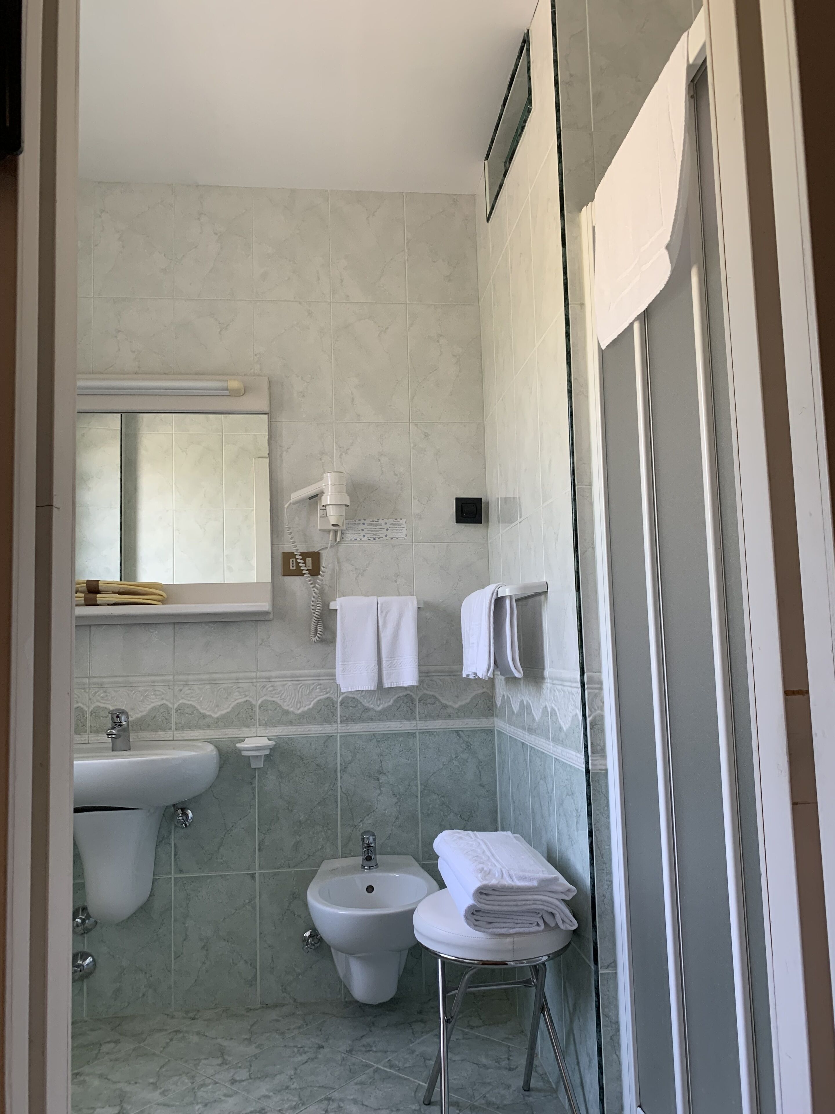 Un baño con lavamanos, bidé y cabina de ducha de vidrio.
