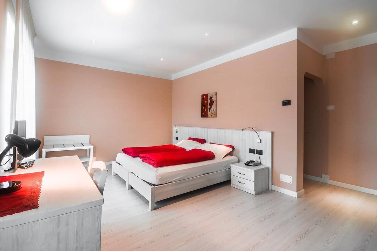 A modern bedroom with a bed, bedside tables, a desk, and a chair.