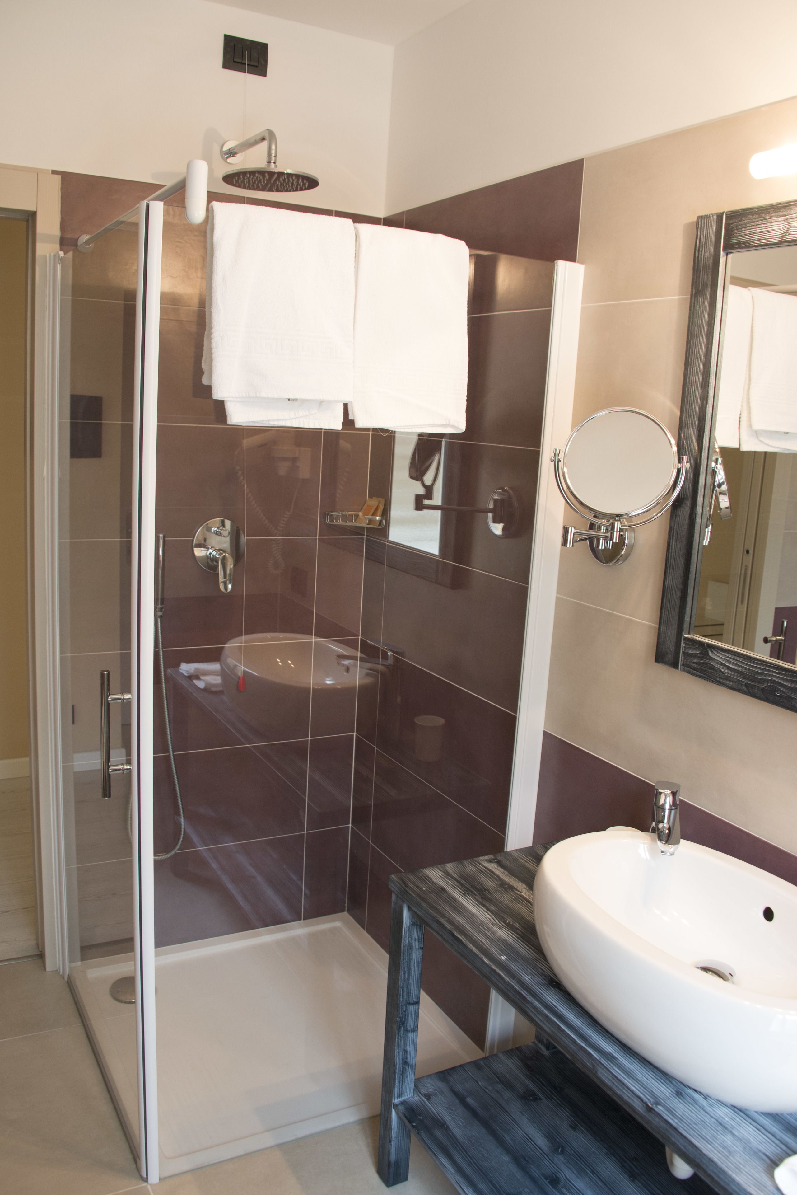 Un baño moderno con cabina de ducha de vidrio, un lavamanos blanco y un espejo grande.