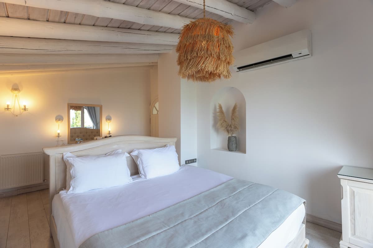 Un dormitorio con cama, lámparas de noche, un espejo, aire acondicionado y un adorno en la pared.