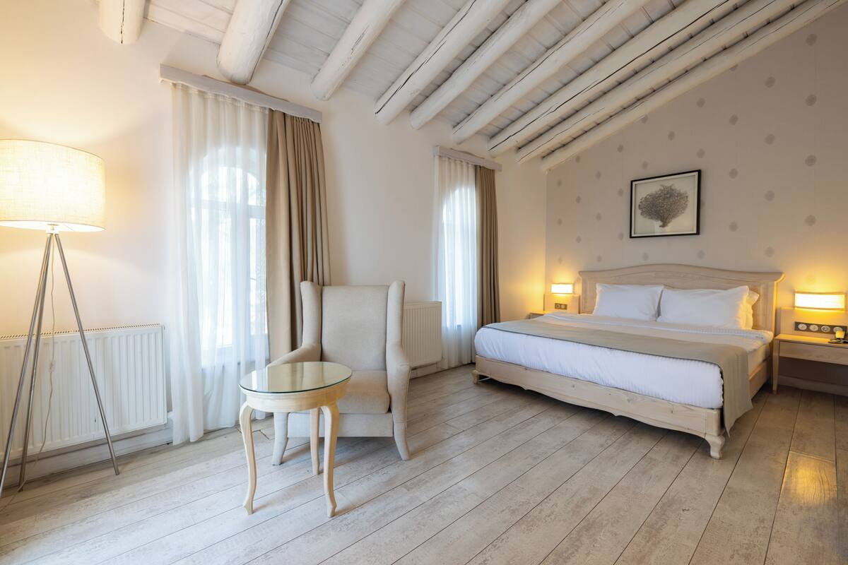 Una habitación de hotel con cama, una silla, una mesa y una lámpara.