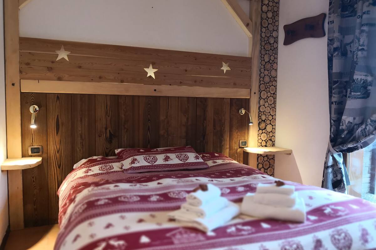 A wooden bed with a star-patterned bedspread and two bedside lamps.