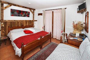 A bedroom with a wooden bed, a red throw blanket, a patterned rug, and a television on the wall. - Chalet del Sole (Sauze d'Oulx)
