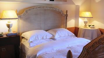A neatly made bed with white linens, two bedside tables with lamps, and a decorative headboard.