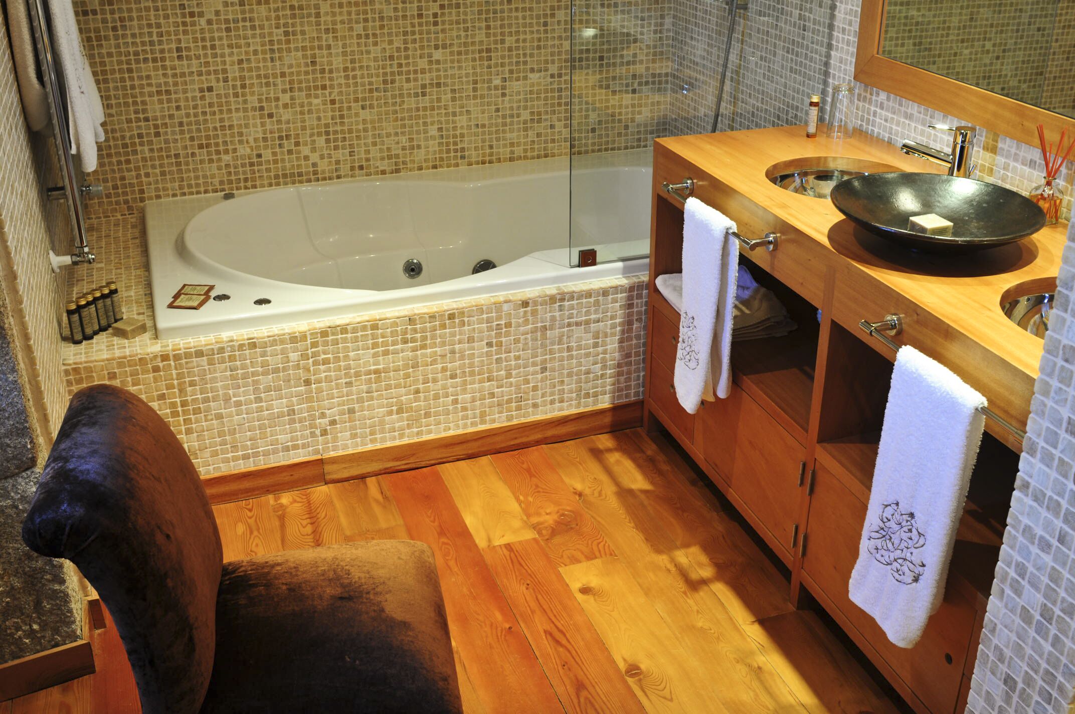 Ein Badezimmer mit einer großen Badewanne, einem Holzkosmetikschrank und einem Spiegel.