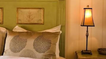 A neatly made bed with patterned pillows, a bedside lamp, and a small bedside table with a bowl.