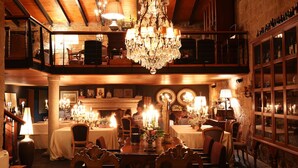 A dining area with a chandelier, tables, chairs, and a wine rack. - Casas do Coro (Meda)