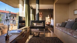 A modern living room with a fireplace, a sofa, a TV, and a dining area with a view of the outside. - Casas do Coro (Meda)