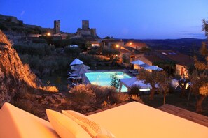 Un área de piscina con sombrillas, una estructura similar a un castillo y edificios circundantes.