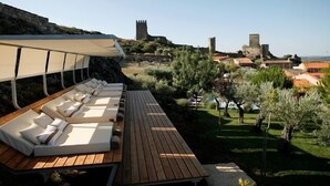 A wooden deck with lounge chairs and a canopy, overlooking a historic town with medieval structures. - Casas do Coro (Meda)