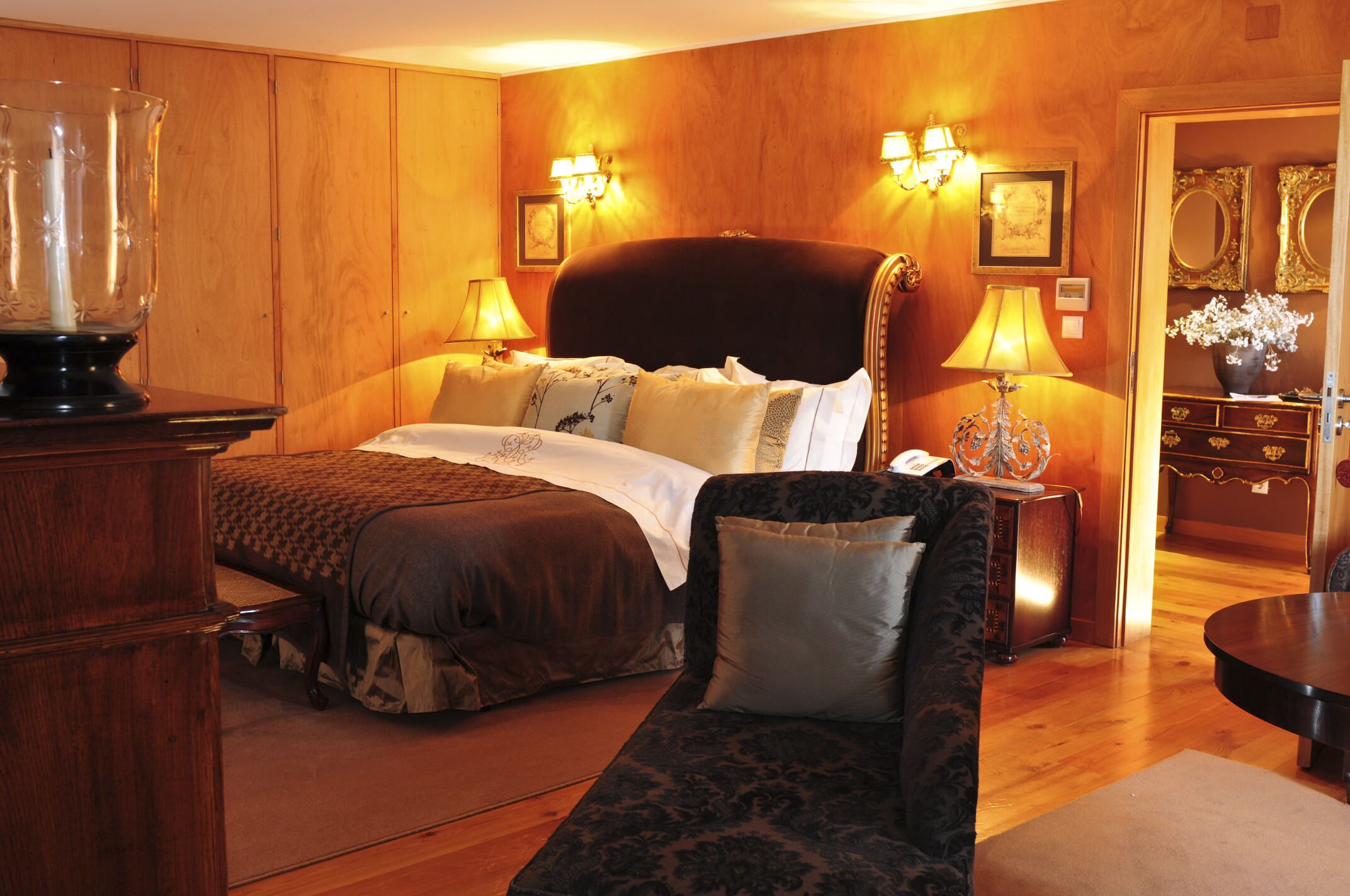 A hotel room with a large bed, a wooden dresser, a sitting area with a sofa, and a small table.