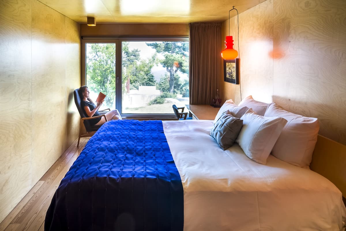 Ein Schlafzimmer mit einem großen Bett, einem Sessel und Blick ins Freie.