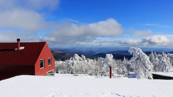 Un edificio rojo con paisaje nevado y montañas al fondo.